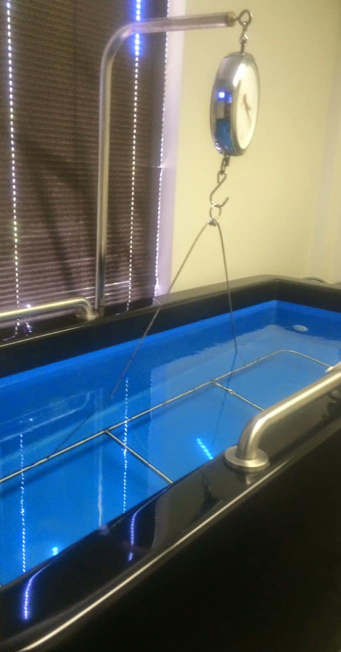 The hydrostatic testing tank at Rawmana Fitness, with its scale and blue-lit water.